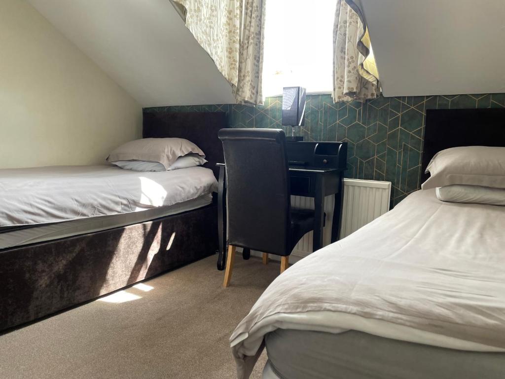 a room with two beds and a desk and a sink at Burton Villa Guest House in York