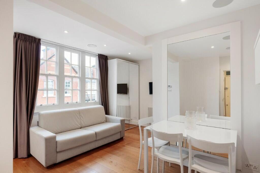 salon z białą kanapą i stołem w obiekcie Beaufort Gem Chelsea Apartment w Londynie