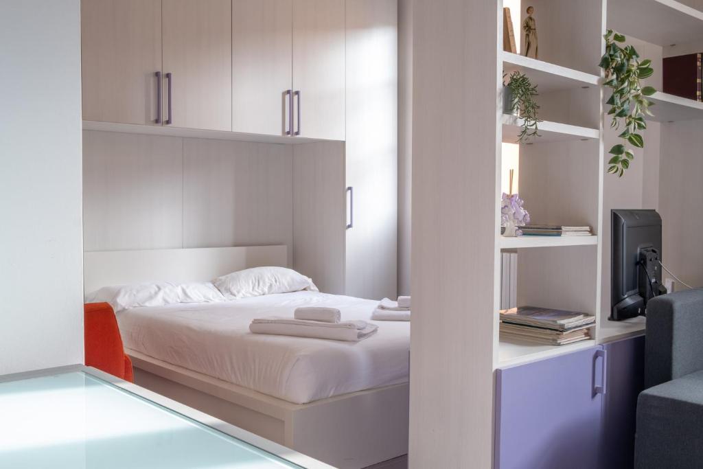 a bedroom with a bed with white walls and shelves at Casa Moro in Crema