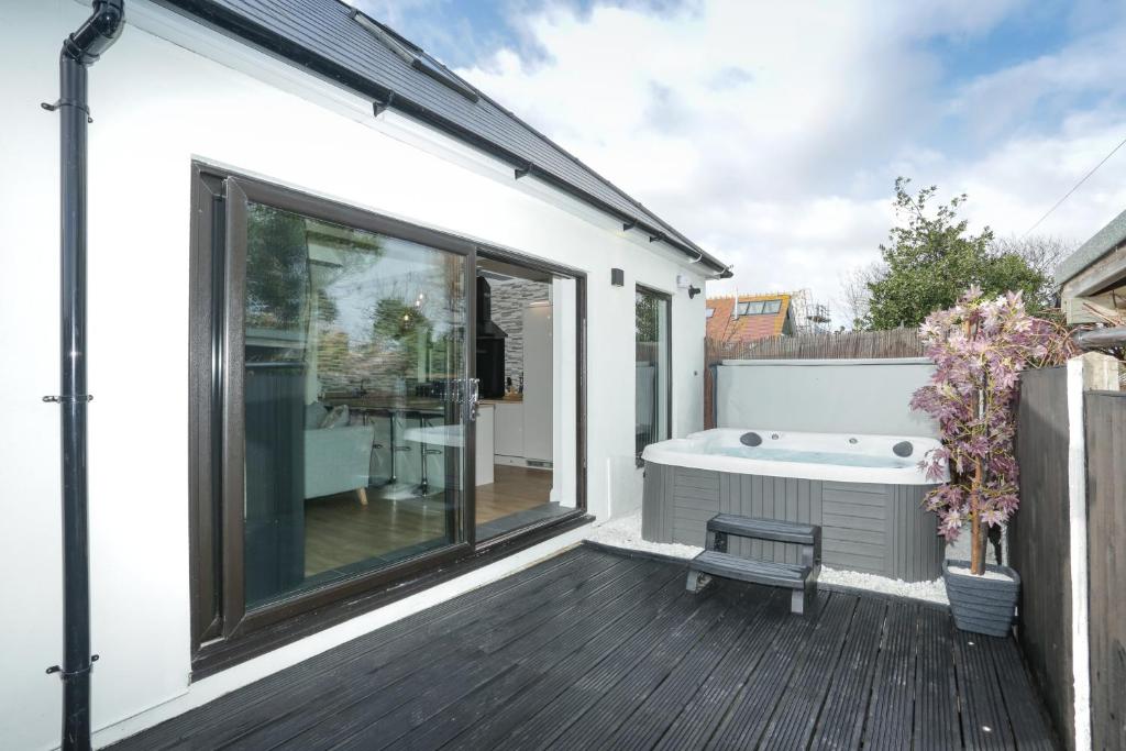 een badkamer met een bad op een terras bij The Broadway Beach House with Hot tub in Kent