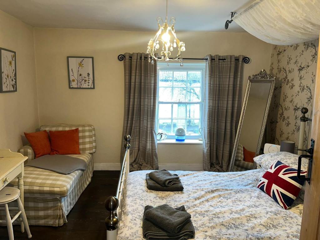 ein Schlafzimmer mit einem Bett, einem Sofa und einem Kronleuchter in der Unterkunft Lavender Cottage, Grade 2 Listed Period Stone Built Cottage In Pickering, North Yorkshire in Pickering