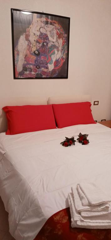 Una cama con sábanas rojas y blancas y flores. en Bella Vista FIDENZA, en Fidenza
