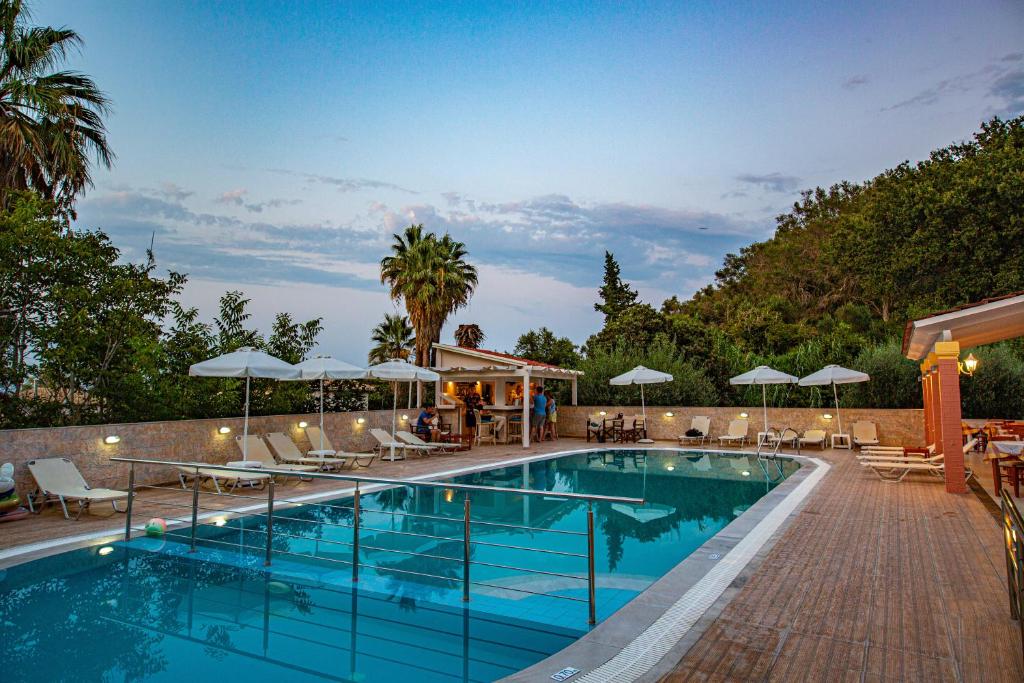 a swimming pool with lounge chairs and umbrellas at Hotel Penelope in Boukari
