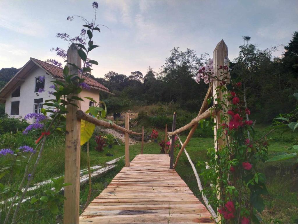 uma passagem de madeira que leva a uma casa com flores em El chalet de Agnes em Villa de Leyva
