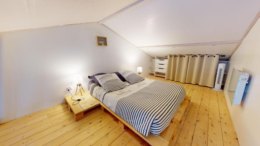 a attic bedroom with a bed and a wooden floor at Charmant pavillon bordelais (logement entier) in Saint-Médard-en-Jalles