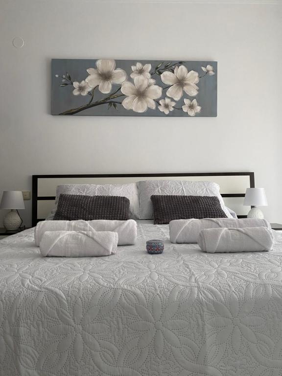 a white bed with two pillows and a painting on the wall at SUEÑOS DEL MAR in Motril