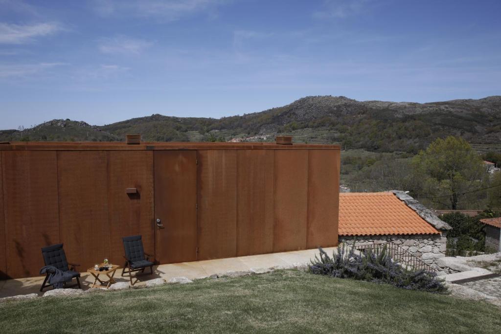 ein großes Holzgebäude mit zwei Stühlen und einem Tisch in der Unterkunft Gerês - Leiras do Tempo - Cottage Tomadinha 3 in Terras de Bouro