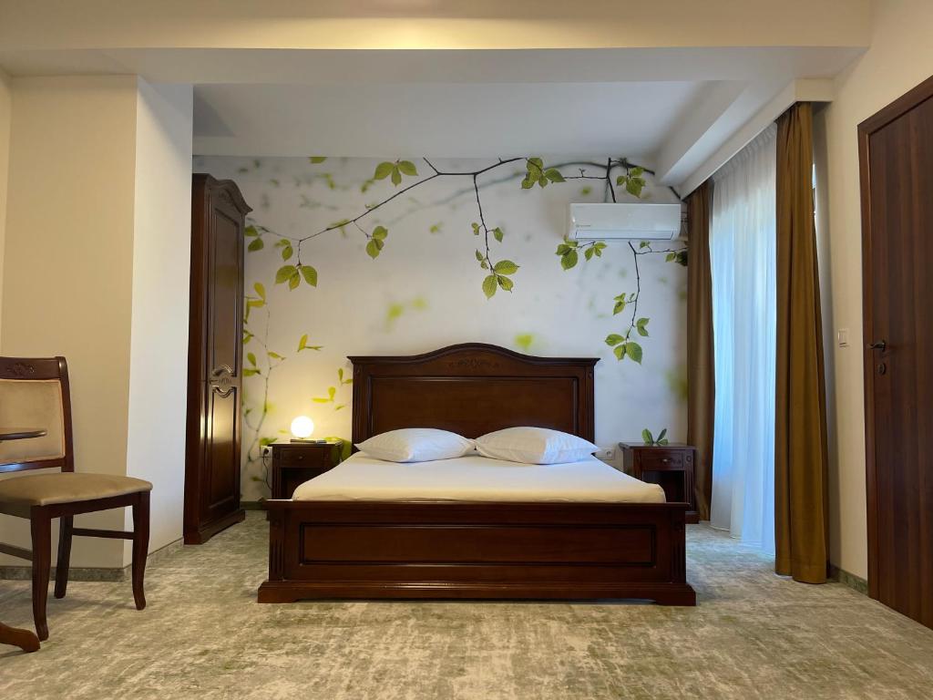 a bedroom with a bed with a branch on the wall at Pensiune Premier in Doctor Petru Groza