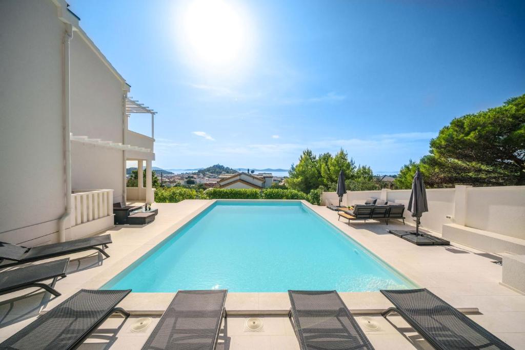 a swimming pool with chaise lounge chairs next to a house at Villa Pearl in Tribunj