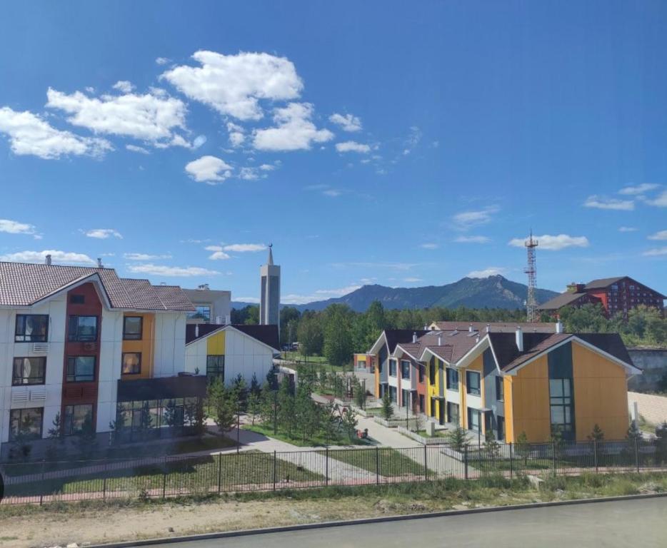 a row of houses in a town with mountains in the background at Апартаменты Promenade Burabay in Borovoye
