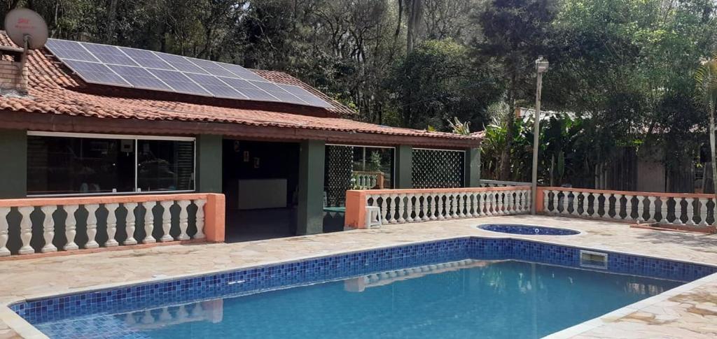 Sitio Terra Azul في جوارولوس: منزل به مسبح وألواح شمسية على سقفه