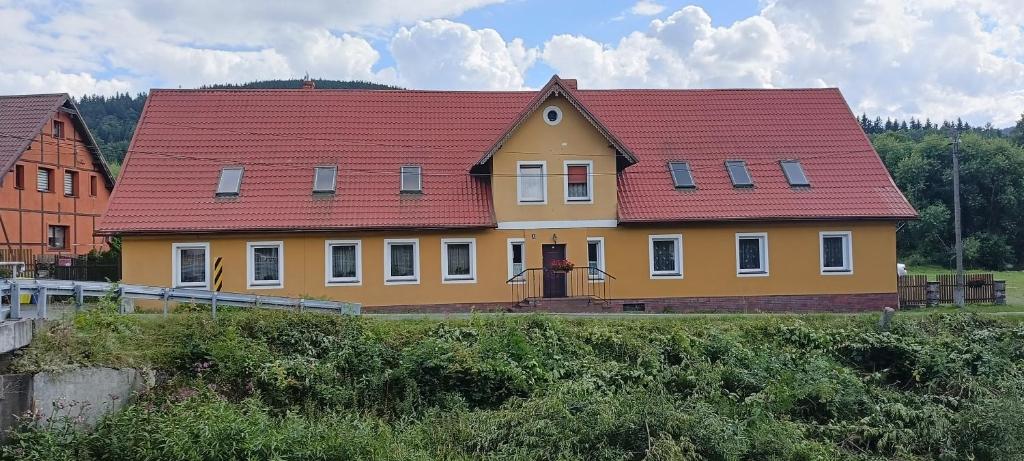 une maison jaune et rouge avec un toit rouge dans l'établissement STANICA, à Nowy Gierałtów
