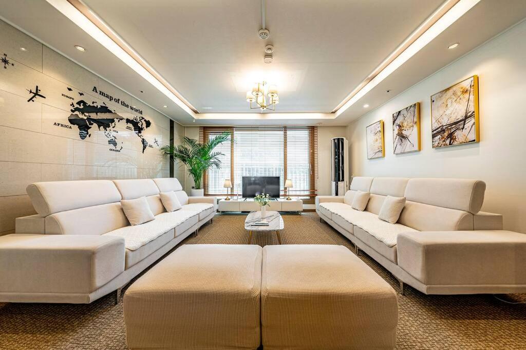 a living room with white couches and a tv at Swa Tailored Serviced Home Near Gwanggyo Stn in Suwon
