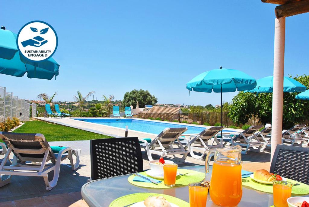 una mesa con comida y zumo de naranja junto a una piscina en Villa Zanzibar by Algarve Vacation, en Olhos de Água
