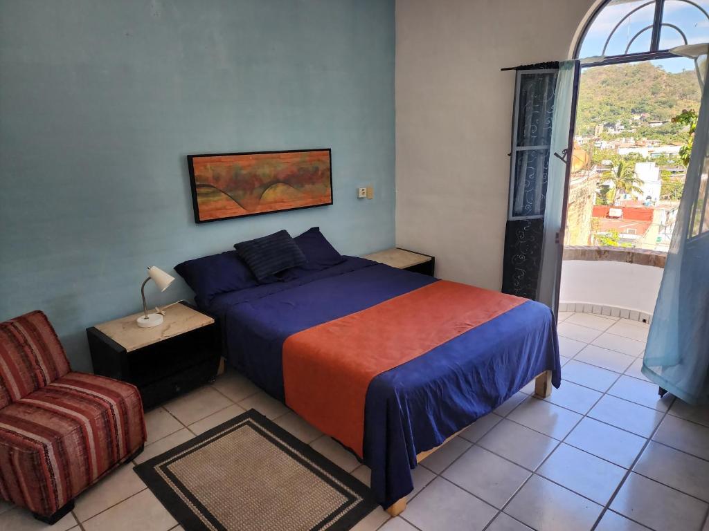 een slaapkamer met een bed, een stoel en een raam bij Casa Marina in Puerto Vallarta