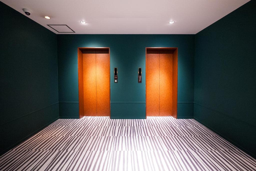 富山市にあるHotel Torni ホテル トルニのオレンジ色のドア2つと緑色の壁が施された空の部屋