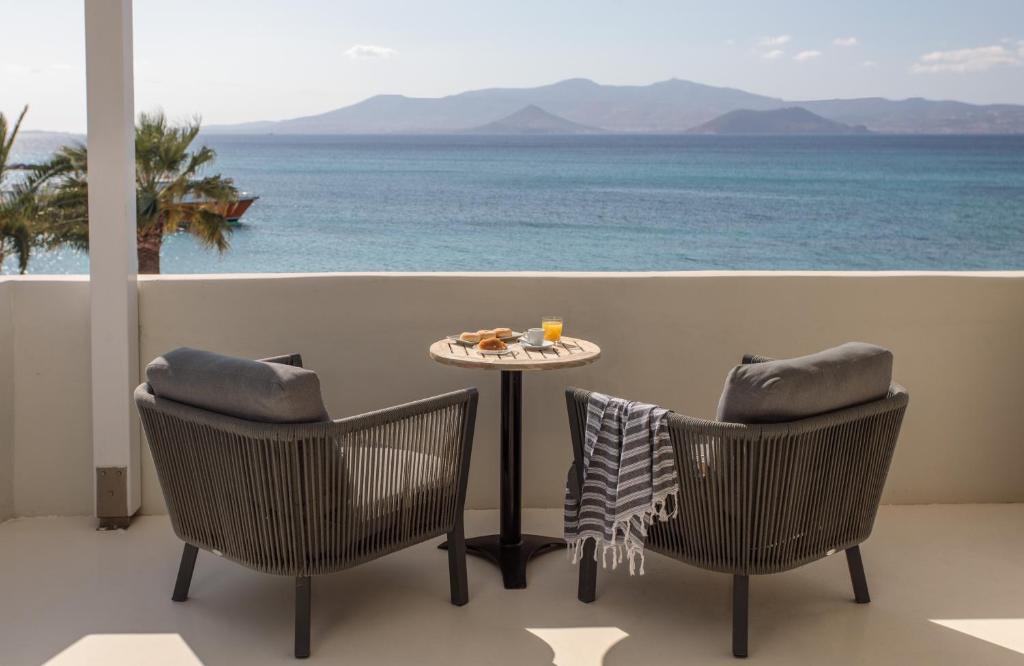 una mesa y sillas en un balcón con vistas al océano en Iria Beach Art Hotel, en Agia Anna de Naxos