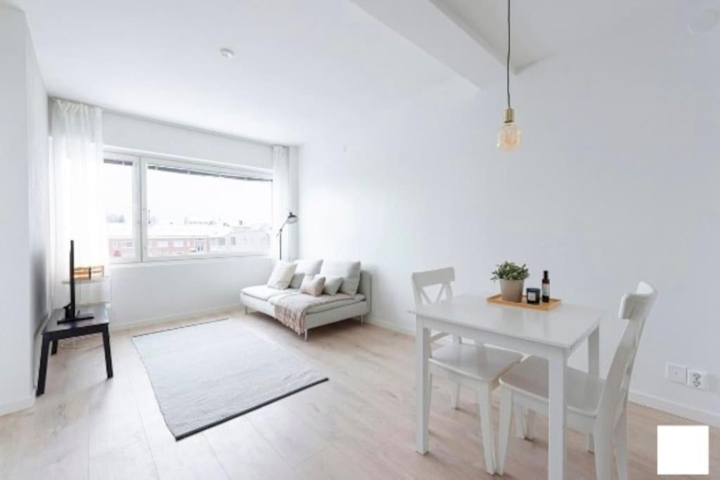 Moderni kaksio ydinkeskustassa في كوبيو: غرفة معيشة بيضاء مع طاولة وأريكة