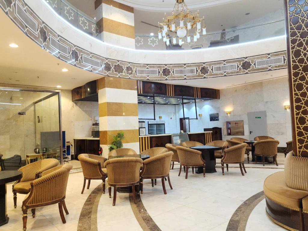 a lobby with tables and chairs in a building at فندق إي دبليو جي العزيزية in Makkah