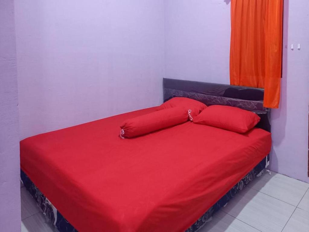 ein rotes Bett mit zwei roten Kissen in einem Zimmer in der Unterkunft HOME STAY HARAPAN 