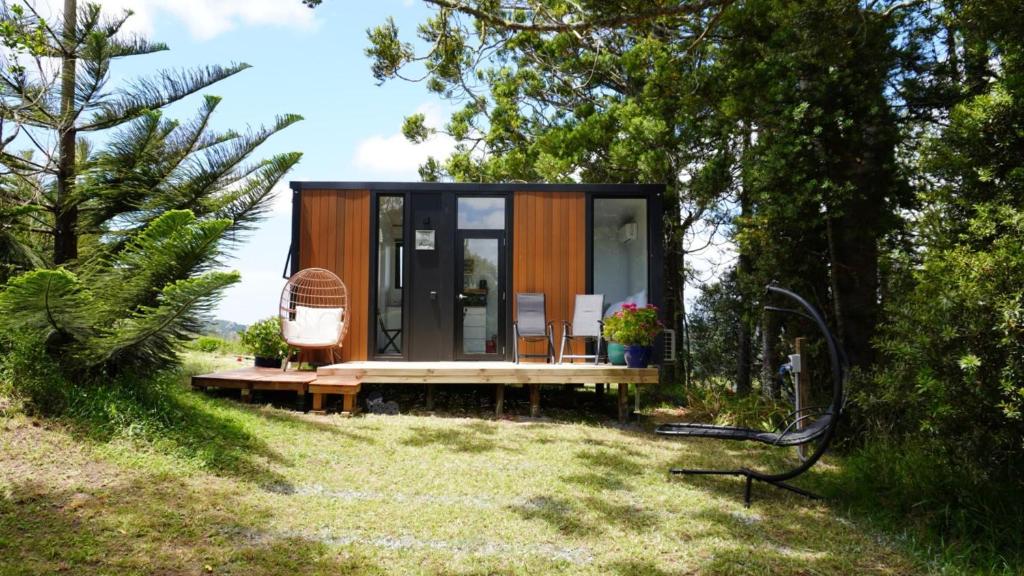 a tiny house in a garden with a bench at The Kauri Retreat 1 in Waitoki