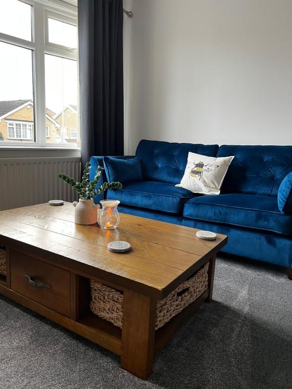 a living room with a blue couch and a wooden coffee table at Sunset Cottage in Stockton-on-Tees
