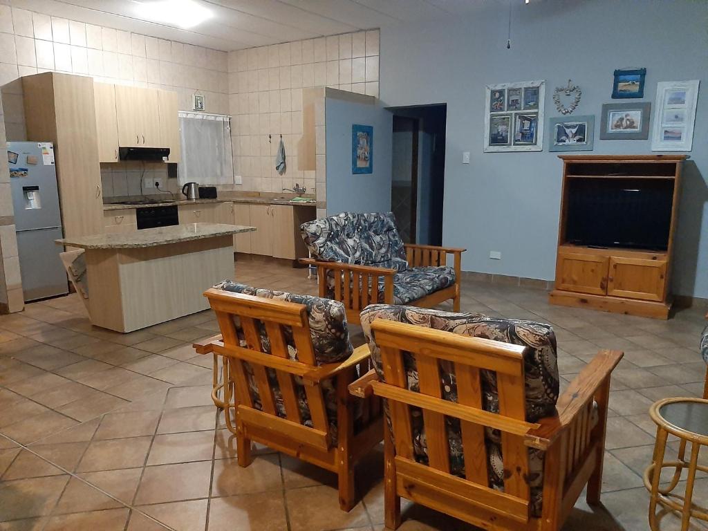 a large living room with chairs and a kitchen at Britsies @ Sea in Mossel Bay