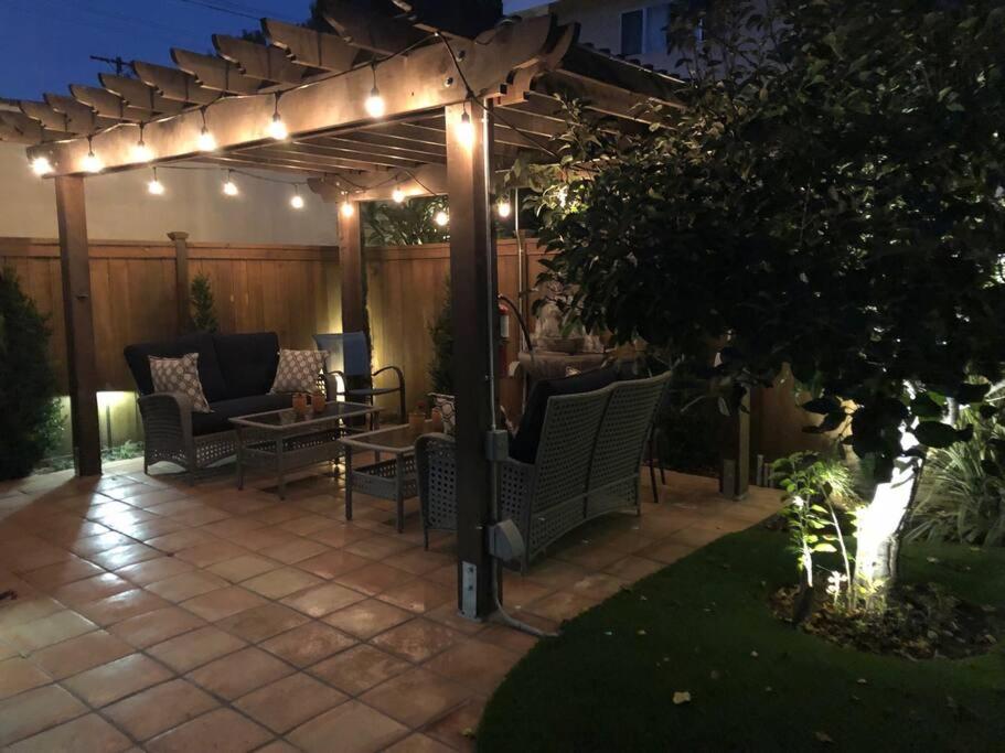 a patio with chairs under a pergola with lights at Long Beach Home Beautiful Private area in Long Beach