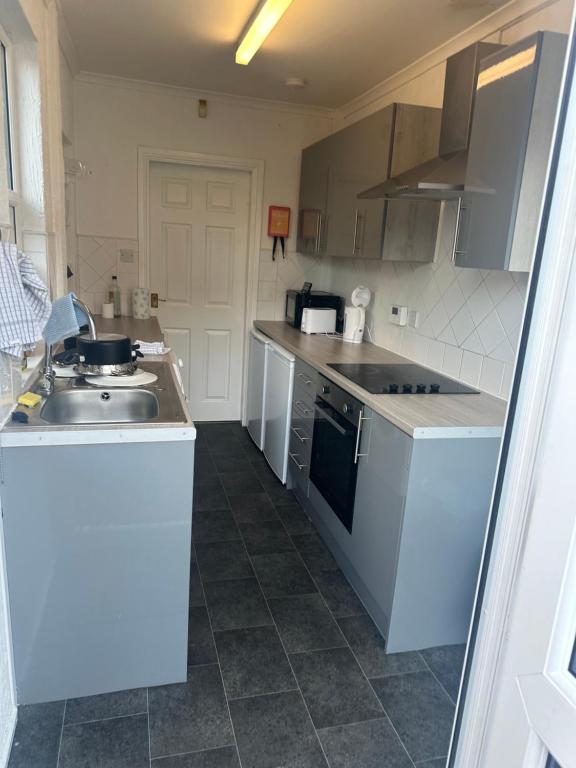 a small kitchen with a sink and a stove at Party house in Derby