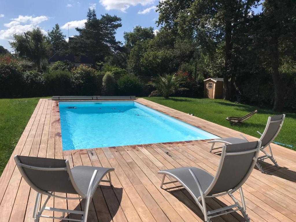 een zwembad met twee stoelen op een houten terras bij Maison Golfe du Morbihan in Saint-Nolff