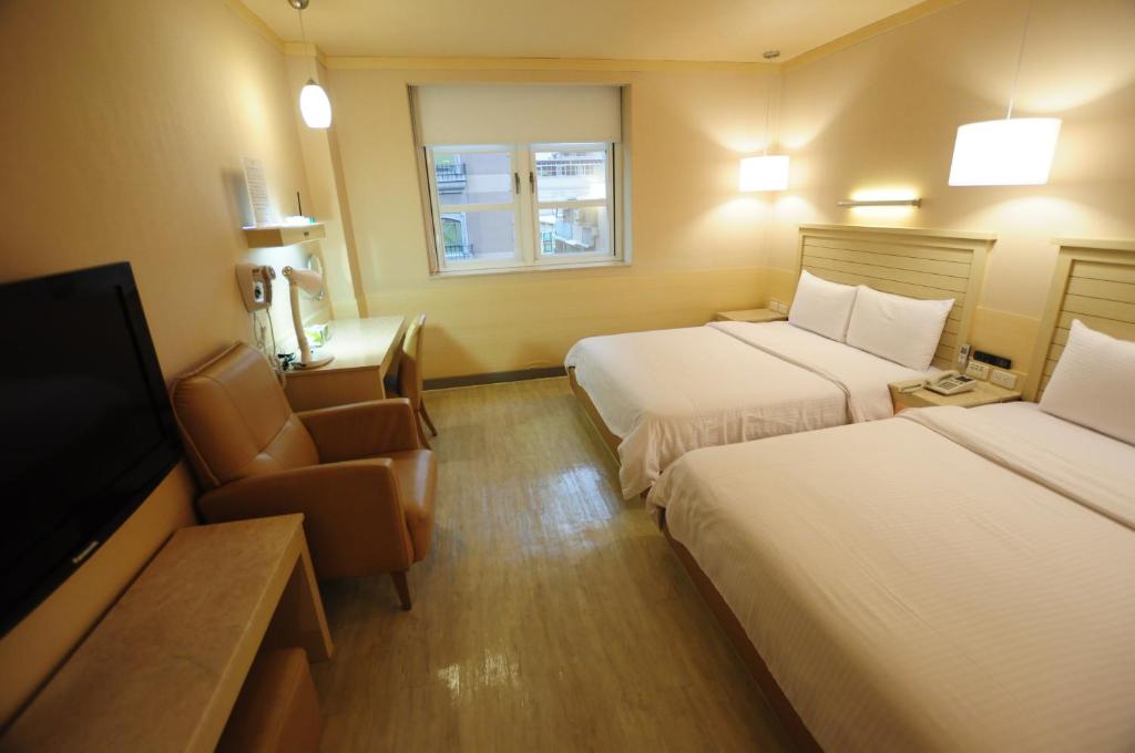 a hotel room with two beds and a flat screen tv at Kindness Hotel - Jhong Jheng in Kaohsiung