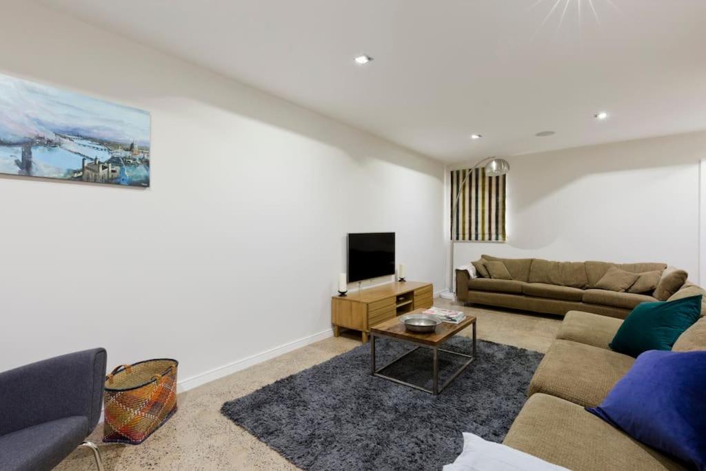 sala de estar con sofá y TV en Modern Town house in Barnes, West London, en Londres