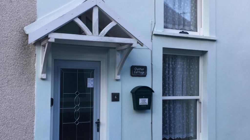 a white house with a door and a mailbox at Oyster Cottage in The Mumbles