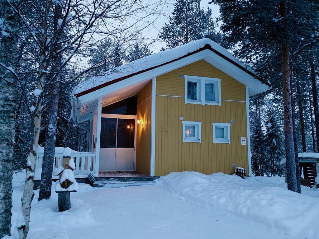 une petite maison jaune avec de la neige au sol dans l'établissement Lapland Forest Lodge, à Rovaniemi