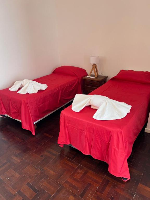 two beds in a room with red sheets and white towels at Share in Buenos Aires
