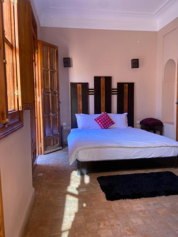 1 dormitorio con 1 cama grande con sábanas blancas y almohadas rojas en Villa les oliviers, en Marrakech