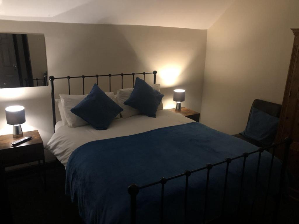 a bedroom with a large bed with blue sheets and pillows at The Old Bath Arms in Frome