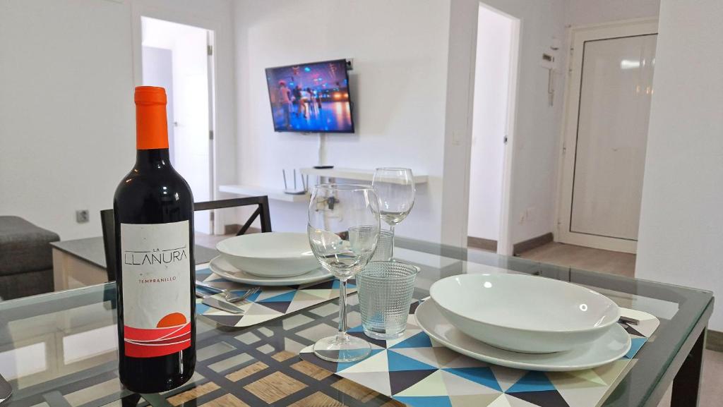 a bottle of wine sitting on a glass table with plates and glasses at Atalaya - Sea View in Adeje