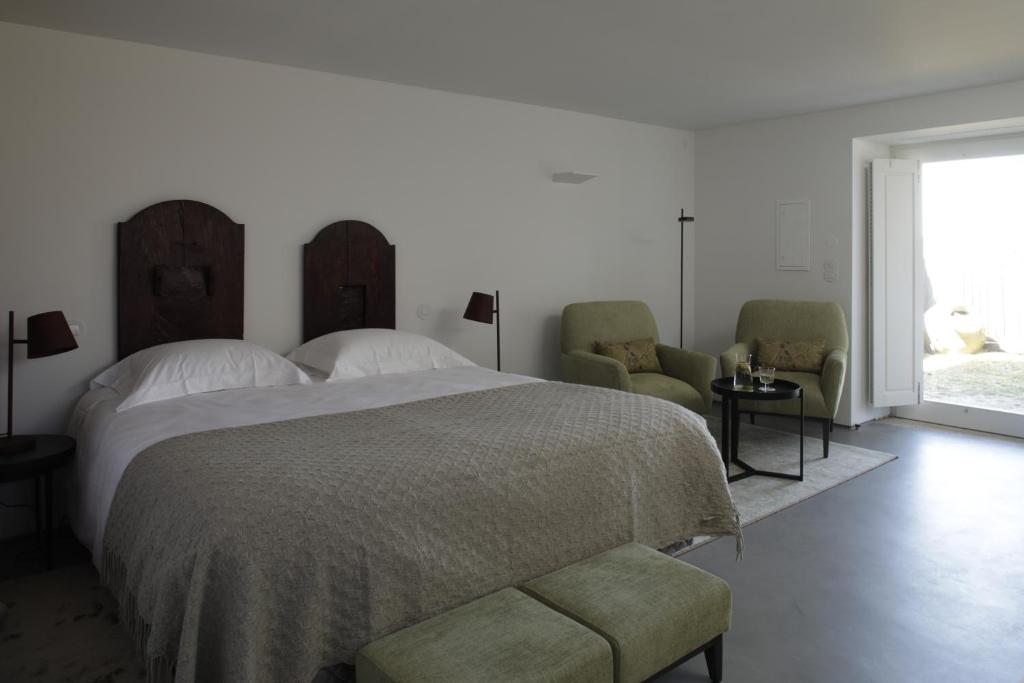 a bedroom with a bed and two chairs and a window at Gerês - Leiras do Tempo - Suite Alecrim in Terras de Bouro