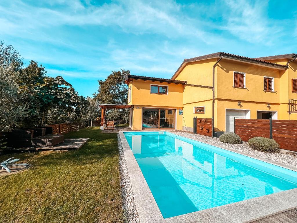 a villa with a swimming pool in front of a house at Olive garden family apartment with private pool in Sežana