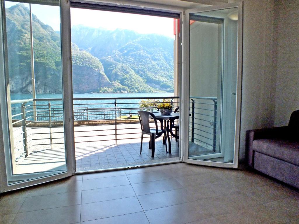 a room with a balcony with a table and a view at Lake Como Casa la Rosa apartment Iris in Abbadia Lariana
