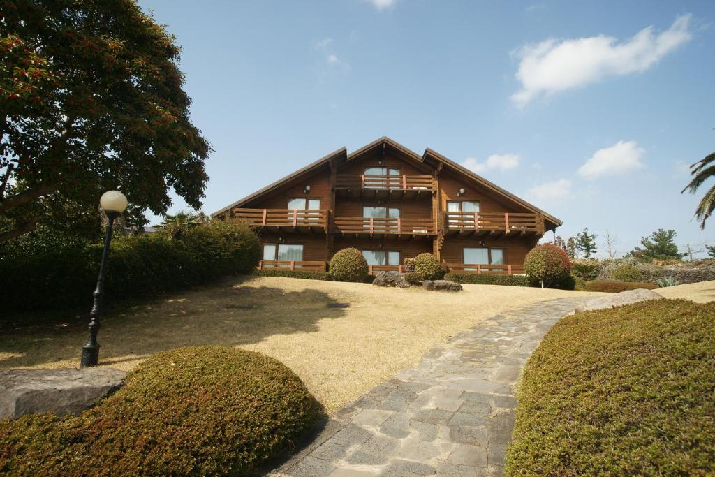 a large wooden house with a pathway in front of it at Sunny Day Jeju in Seogwipo