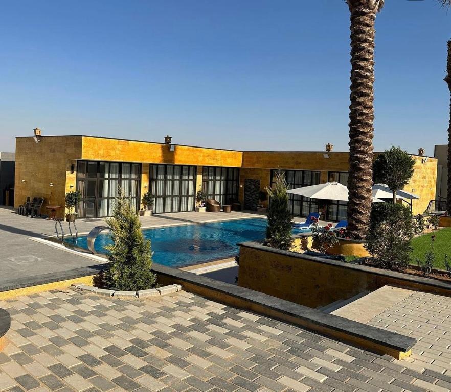 a building with a swimming pool and a palm tree at AL-TARAF FARM in Umm el ‘Amad