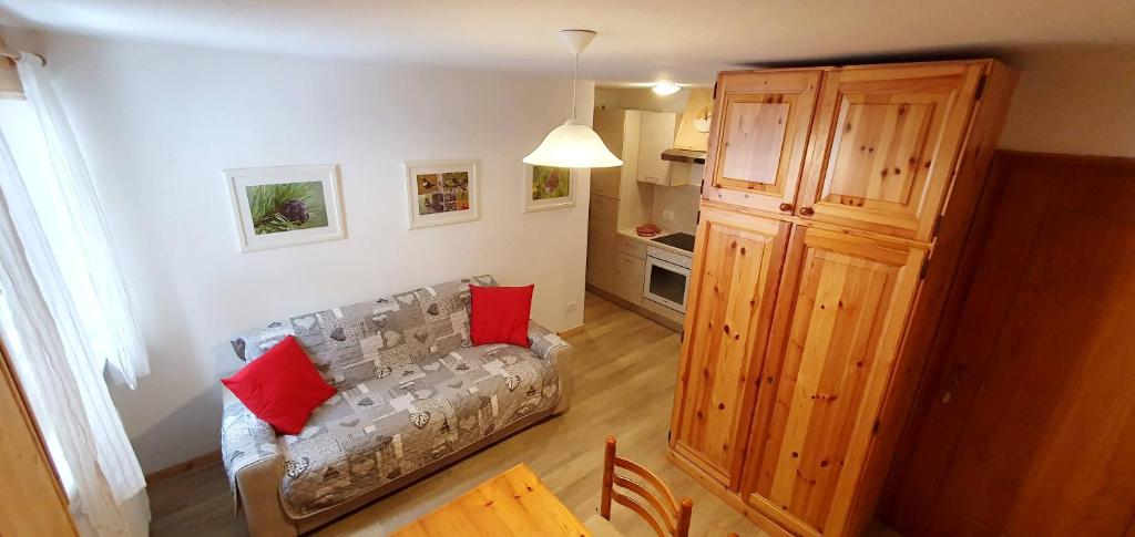 un salon avec un canapé avec des coussins rouges dessus dans l'établissement Appartamento Pampeago 10, à Tesero