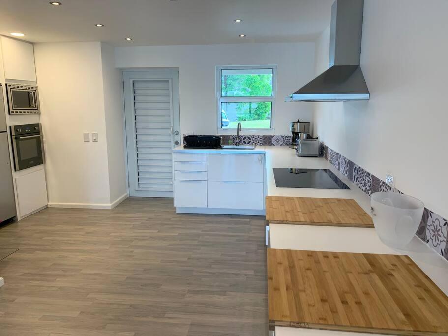 a kitchen with white counters and a wooden floor at Luxury Waterfront Villa 249C South Beach in Jolly Harbour