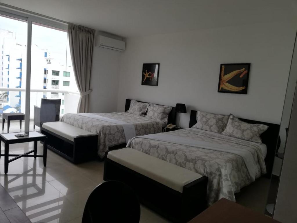 a hotel room with two beds and a balcony at Playa Blanca Town Center Suites in Río Hato