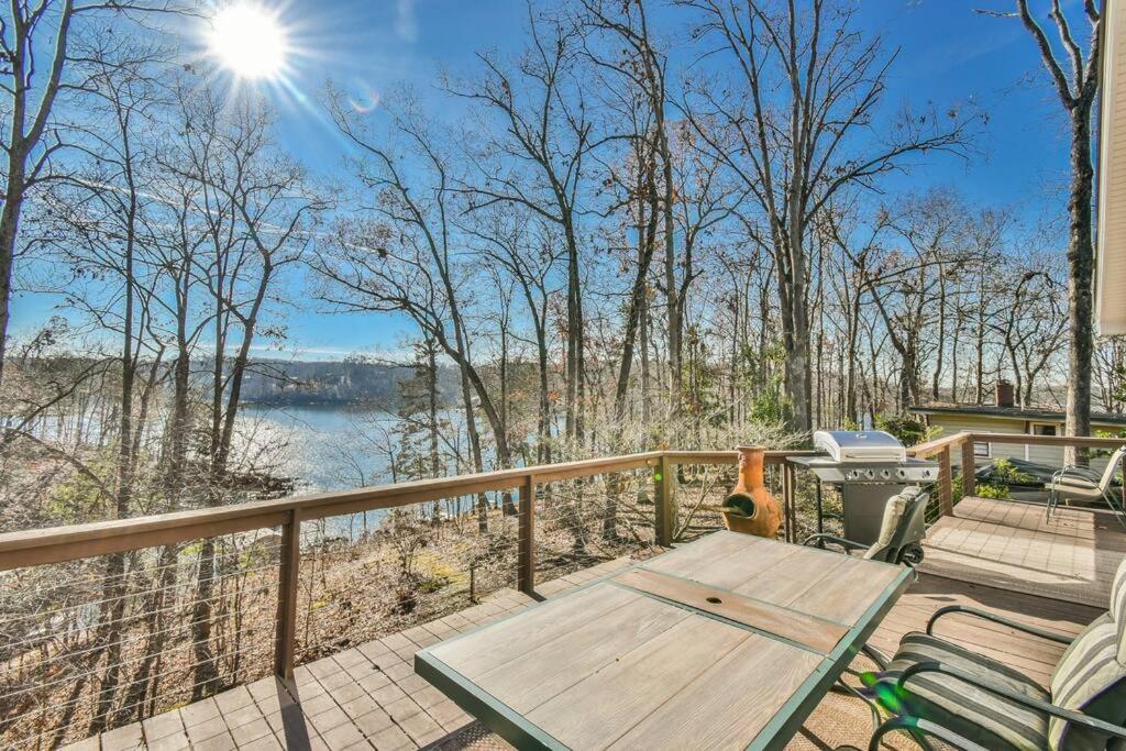una terraza con mesa y sillas de madera y vistas al agua en Tranquil Lakeside Getaway with Modern Comfort, en Flowery Branch