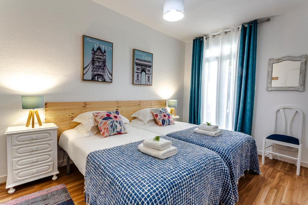 Duas camas individuais num quarto com cortinas azuis em A Casa da Tia em São Vicente