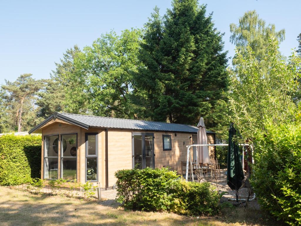 een klein huis in een tuin met bomen bij Luxury chalet on cozy family campsite. in Garderen