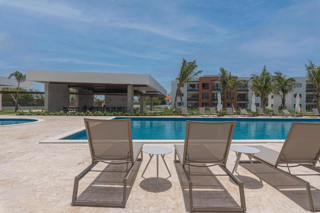 un grupo de sillas sentadas junto a una piscina en Apartamento 2 habitaciones piscina cerca de playa, en Punta Cana